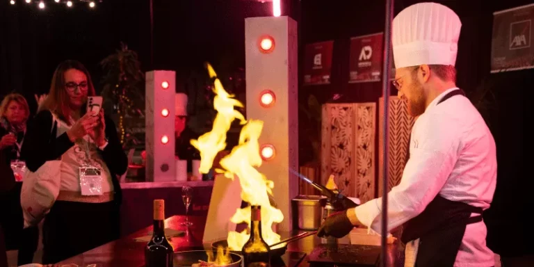 Chef Flyin'Chef réalisant un flambage spectaculaire en direct lors d'un show culinaire