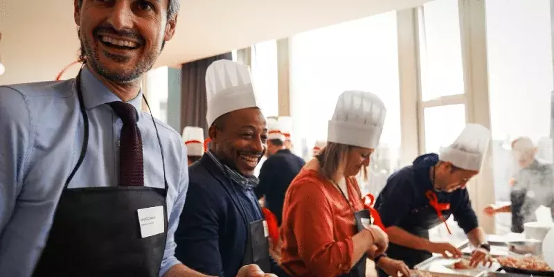 Participants souriants en toque lors d'un atelier de team building culinaire animé par Flyin'Chef
