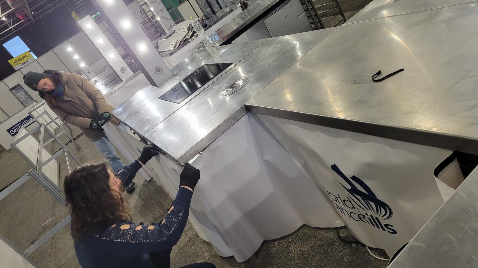Deux techniciens Flyin'Chef ajustent un plan inox pendant le montage d'un îlot de cuisine