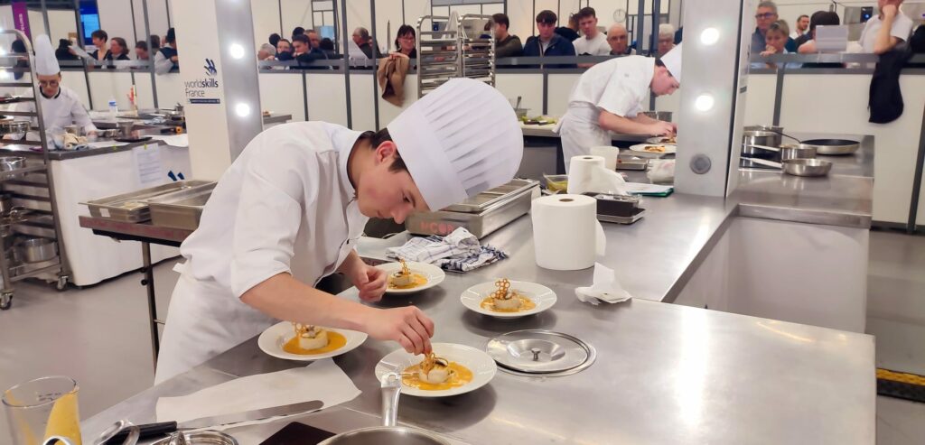Candidat dressant cinq assiettes devant le public aux sélections WorldSkills des Pays de la Loire à Angers
