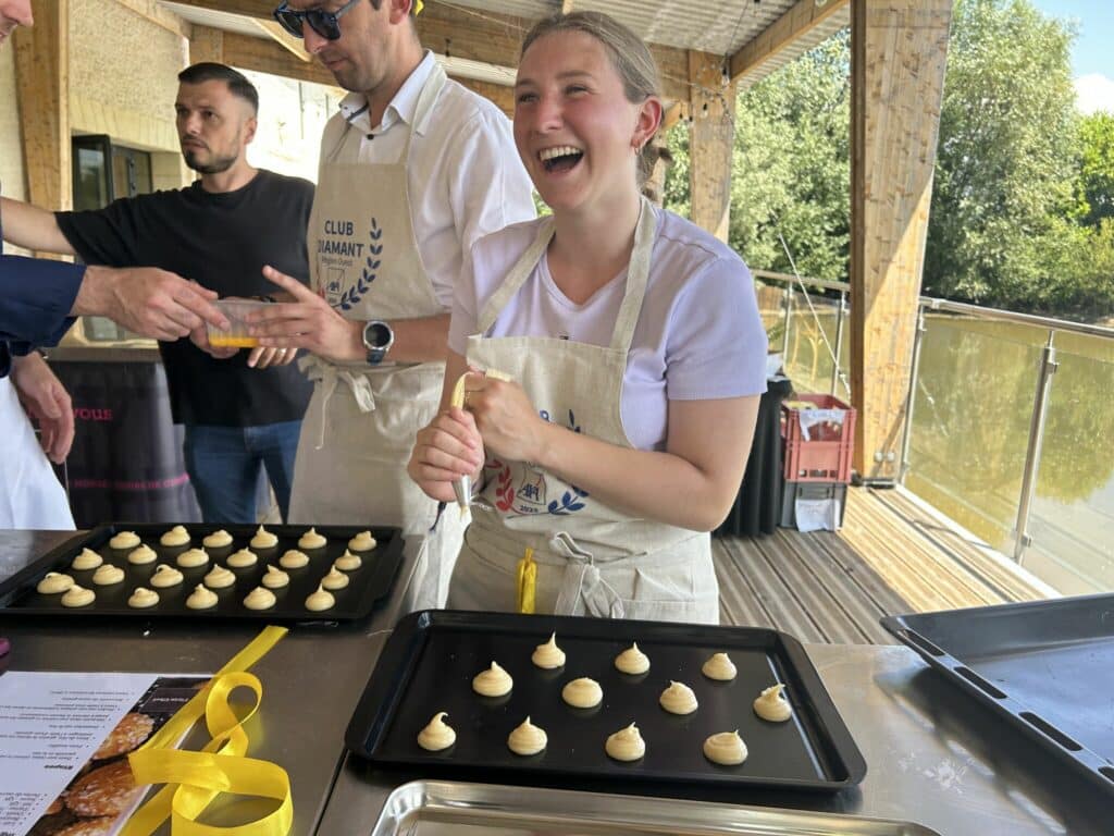 Participante riant en pochant des choux pendant un challenge pâtisserie Flyin'Chef