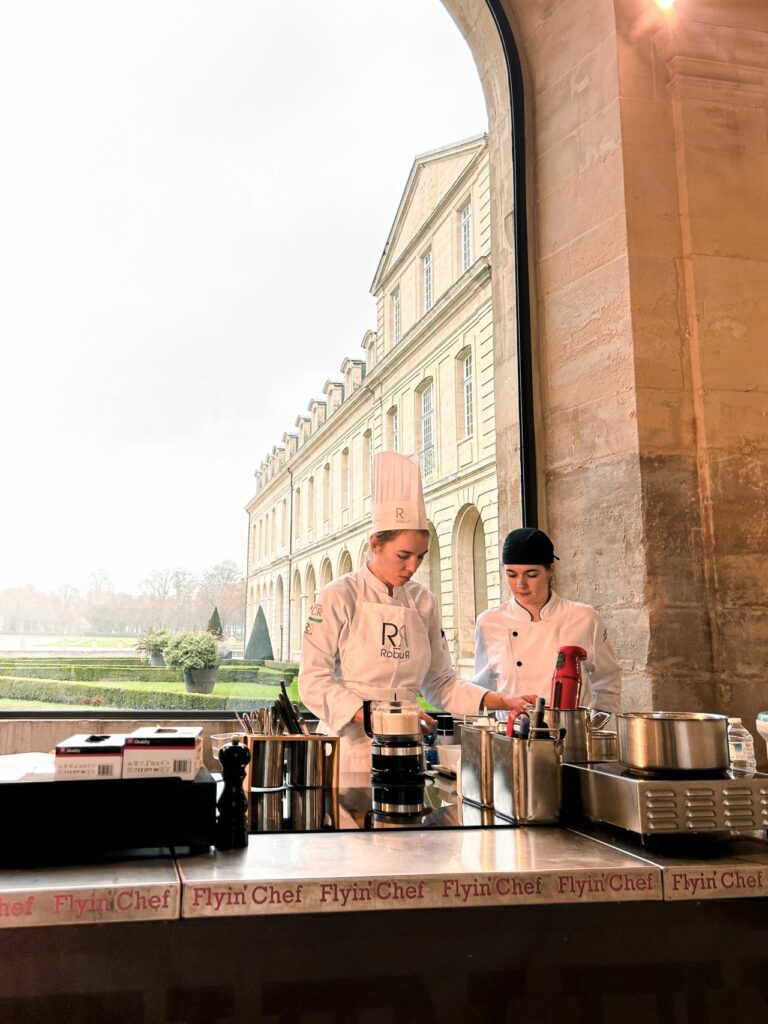 Candidate du Concours Jeunes Talents en épreuve sur une cuisine mobile Flyin'Chef, avec vue sur les jardins de l'Abbaye aux Dames de Caen