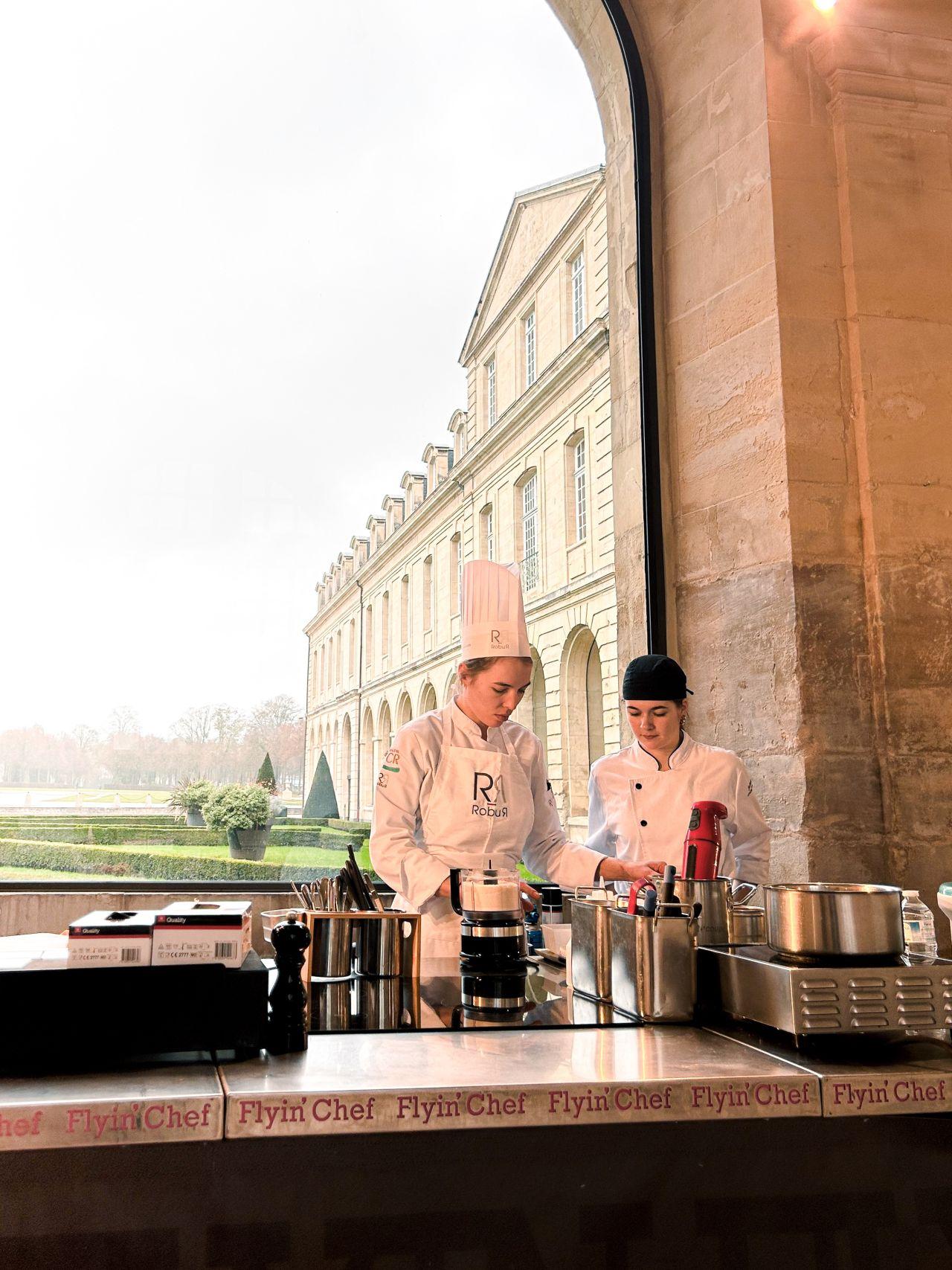 Candidate du Concours Jeunes Talents en épreuve sur une cuisine mobile Flyin'Chef, avec vue sur les jardins de l'Abbaye aux Dames de Caen