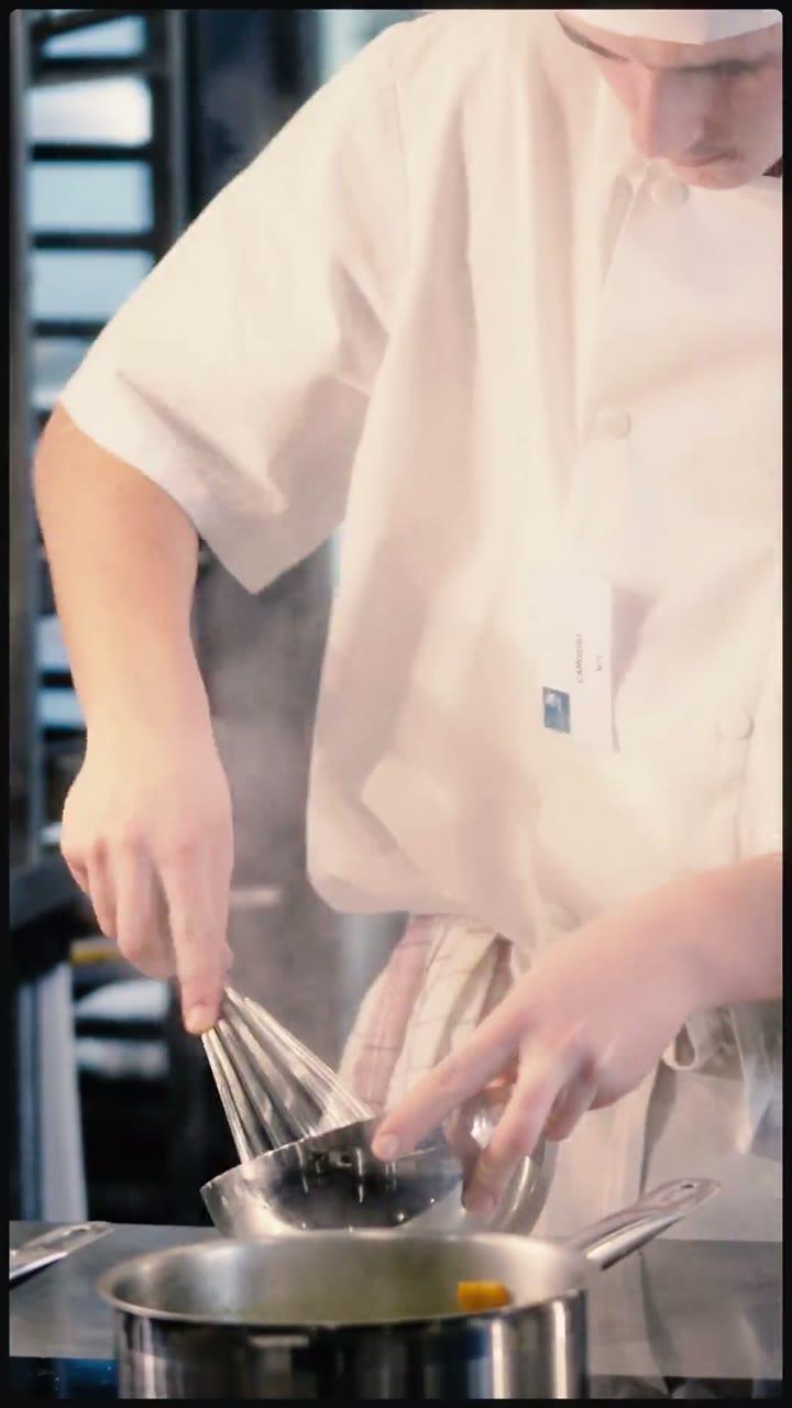 Candidat en toque fouettant une sauce sur un poste de cuisine de concours Flyin'Chef aux WorldSkills de Metz 2025