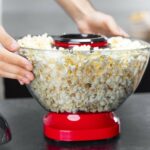 Bol amovible de la machine à pop-corn retiré à deux mains, rempli de pop-corn