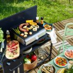 Plancha pro installée en terrasse avec un buffet de grillades et de légumes