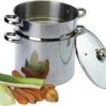 Couscoussier inox ouvert, couvercle en verre posé à côté, avec poireau, carottes et oignon